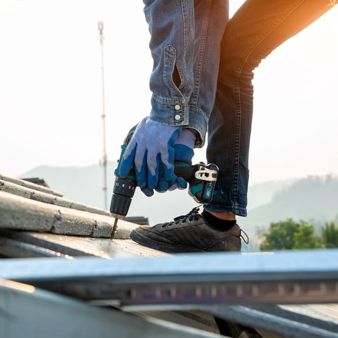 A roofer is installing a roof with a drill.